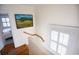 Bright stairway features a wooden banister, white walls and trim, and an eye-catching painting for added visual appeal at 24 Archdale St, Charleston, SC 29401