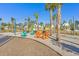 Inviting community area with colorful Adirondack chairs, picnic tables, string lights, and palm trees against a clear blue sky at 282 Great Lawn Dr, Summerville, SC 29486