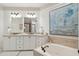 This primary bathroom features a double vanity, granite countertops, wainscoting, jacuzzi tub, and elegant decor at 3 37Th Ave, Isle of Palms, SC 29451