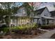 Cozy two-story home with a front porch featuring seating amidst a meticulously landscaped front yard at 308 Scholar Way, Summerville, SC 29486