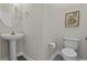 A half bathroom featuring gray flooring, toilet, and round mirror over pedestal sink at 311 Amaryllis Ave, Summerville, SC 29483