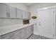 Well-organized laundry room with gray cabinets, quartz countertop, and stylish patterned floors at 3154 Hugh Bennett Dr, Johns Island, SC 29455