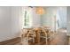 Elegant dining room featuring a wooden table set for six, complemented by a rattan pendant light and natural light at 325 Pine Crest View, Summerville, SC 29486