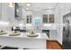 Modern white kitchen with stainless steel appliances, subway tile backsplash, and a breakfast bar with pendant lighting at 4 Addison St, Charleston, SC 29403