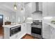 Open kitchen with stainless steel appliances, gas range, custom white cabinetry, and hardwood flooring at 4 Addison St, Charleston, SC 29403