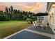 Outdoor patio with a table and seating, overlooking a spacious green yard under a beautiful sunset at 440 Four Seasons Blvd, Summerville, SC 29486