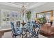 Elegant dining room with chandelier, shuttered windows, glass table and six patterned blue dining chairs at 440 Four Seasons Blvd, Summerville, SC 29486