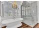 Elegant bathroom featuring a soaking tub, a glass enclosed shower, tile surround, and wood floors at 509 Gilberts Lndg, Mount Pleasant, SC 29464