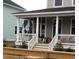 Inviting front porch view with dogs sitting on stairs of charming home featuring white columns and bright blue door at 5153 Celtic Dr, North Charleston, SC 29405