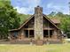 Charming log home with a stone chimney and large windows, surrounded by a well-maintained yard at 5354 Ceva Dr, Hollywood, SC 29449