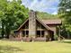 Inviting log home featuring a stone chimney, a spacious deck, and beautifully landscaped lawn at 5354 Ceva Dr, Hollywood, SC 29449