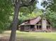 Log cabin home with stone chimney, wood deck, and a screened porch nestled among lush trees at 5354 Ceva Dr, Hollywood, SC 29449