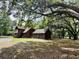 Exterior view of a log home with a two-car garage, a stone chimney, and lush surrounding landscape at 5354 Ceva Dr, Hollywood, SC 29449