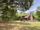 Exterior log cabin with a stone chimney, surrounded by trees, plus a cat house and other outbuildings at 5354 Ceva Dr, Hollywood, SC 29449