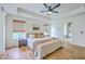 Bright bedroom featuring a ceiling fan, tray ceiling, wood floors, and access to the Primary bath at 5497 Alpine Dr, Summerville, SC 29483