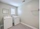 Well-lit laundry room with washer, dryer, window, shelf and a metallic trash can at 5497 Alpine Dr, Summerville, SC 29483