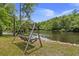 Tranquil river view from a comfortable wooden swing with lush trees and vegetation at 5653 Wire Rd, Branchville, SC 29432