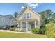 Charming two-story home featuring light yellow siding, a quaint front porch, and manicured landscaping at 7414 Purser Ln, Hanahan, SC 29410