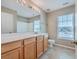 Bright bathroom featuring tile floors, double windows, light wood cabinets, white counter, and a large mirror for good lighting at 7477 Painted Bunting Way, Hanahan, SC 29410