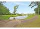 Scenic pond reflecting the sky with a winding paved path, green trees, and distant buildings at 81 Crossandra Ave, Summerville, SC 29483