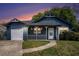 Charming blue home with a white porch, green lawn, and attached garage at sunset at 8268 Timberidge Ct, North Charleston, SC 29420