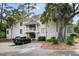 A bright, multi-story condo featuring a stairway, balcony, mature trees, and convenient parking at 856 Club Cottage Rd, Edisto Beach, SC 29438