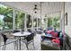 Relax on this screened-in patio with a swing, seating, dining, and views of the landscaped backyard and trees at 856 Club Cottage Rd, Edisto Beach, SC 29438