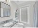 Well-lit bathroom with a marble countertop vanity and a shower with blue curtain at 103 Fishburne St, Charleston, SC 29403