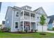 Beautiful two-story home featuring a cozy front porch with hanging flowers and a well-manicured lawn at 1100 Saltwater Cir, Johns Island, SC 29455