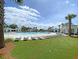 A luxurious pool area with lounge chairs, manicured grass, palm trees, and pristine white buildings at 1472 Longspur Dr, Mount Pleasant, SC 29466