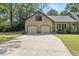 Attached two-car garage with a long driveway and manicured lawn, surrounded by lush landscaping at 2144 Pinopolis Rd, Pinopolis, SC 29469
