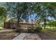 Expansive brick home with multiple entrances and a large wooden deck, surrounded by mature trees and landscaped grounds at 228 Dogwood Trl, Harleyville, SC 29448