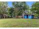 View of cozy blue home with brick chimney, swing, and lush green lawn and landscaping at 228 Dogwood Trl, Harleyville, SC 29448