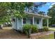 Charming blue cottage with a covered porch, lush greenery, and a well-maintained yard at 228 Dogwood Trl, Harleyville, SC 29448