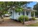 Charming blue cottage with a covered porch, lush greenery, and a well-maintained yard at 228 Dogwood Trl, Harleyville, SC 29448