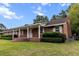 Charming brick home with a long covered porch and meticulously landscaped yard at 228 Dogwood Trl, Harleyville, SC 29448