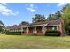 Charming brick home with a long covered porch and mature landscaping at 228 Dogwood Trl, Harleyville, SC 29448