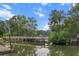 Scenic view of a wooden bridge crossing a calm lake, surrounded by lush greenery and blue skies at 228 Dogwood Trl, Harleyville, SC 29448