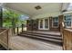 Covered back patio with carpeted steps and wooden railings, offering a cozy spot to enjoy the tranquil outdoor setting at 228 Dogwood Trl, Harleyville, SC 29448