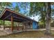 A spacious covered pavilion with wooden benches, perfect for outdoor gatherings, sits beside a charming blue building at 228 Dogwood Trl, Harleyville, SC 29448
