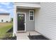 Front entryway featuring a black door with a wreath, adjacent to grey vertical siding at 244 Wild Strawberry Ln, Moncks Corner, SC 29461