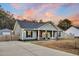 Charming home exterior featuring a lovely front porch with rocking chairs and beautiful sunset in background at 255 S Railroad Ave, Ridgeville, SC 29472