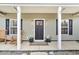 Inviting front porch with decorative plants, rocking chairs and a modern front door at 255 S Railroad Ave, Ridgeville, SC 29472
