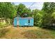 Image showcases a backyard with a blue home and lush surrounding trees at 2654 Harvey Ave, North Charleston, SC 29405
