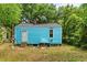 Backyard view of a blue home's exterior, lush greenery, and a chimney at 2654 Harvey Ave, North Charleston, SC 29405