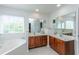 Bright bathroom featuring double vanities with wooden cabinets, a jacuzzi tub, and a large mirror at 3025 Buckeley Cir, Charleston, SC 29414