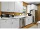 Bright kitchen features stainless steel appliances, white cabinets, and wood plank walls and floors at 3320 Myrtle St, Edisto Island, SC 29438
