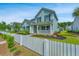 Charming two-story home with a white picket fence, manicured landscaping, and light teal siding at 3941 Bessemer Rd, Mount Pleasant, SC 29466