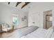 Bright bedroom features exposed beams, modern chair, and access to bathroom with glass shower, great natural light at 42 Poinsett St, Charleston, SC 29403