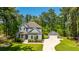 Aerial view of a two-story home with well-manicured lawn and separate garage, surrounded by lush green trees, on a sunny day at 474 Woodspring Rd, Mount Pleasant, SC 29466